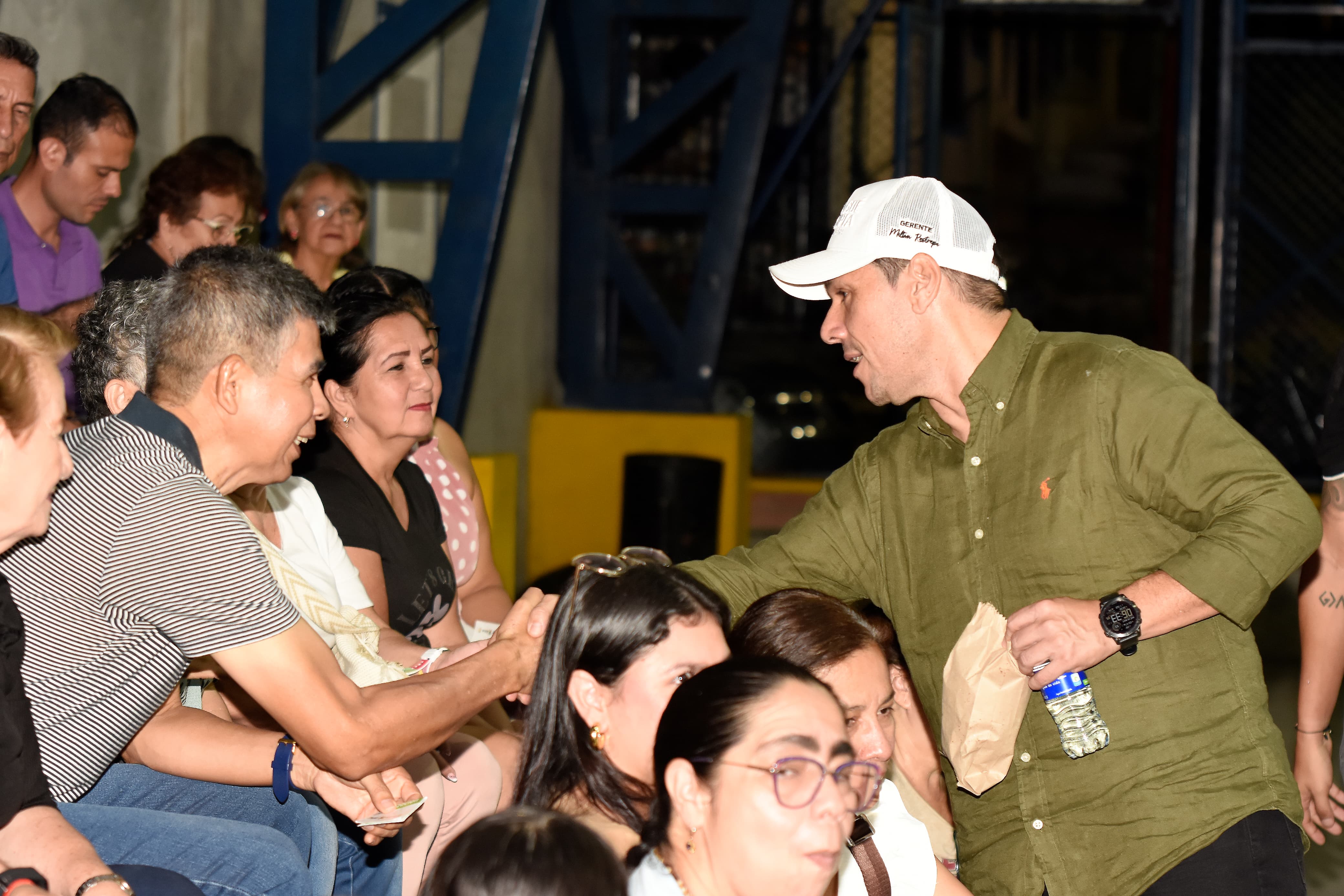 Funcionarios conversan con una residente del barrio mostrando un cartel informativo sobre el mejoramiento del entorno comunitario